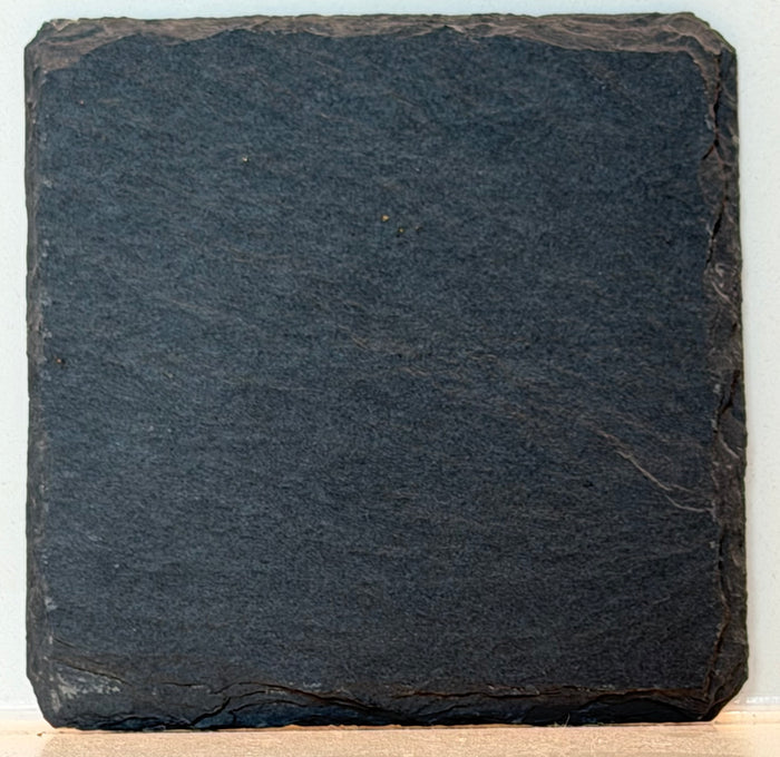 Two black slate coasters with personalized engraved text or monogram on dark stone