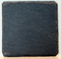 Two black slate coasters with personalized engraved text or monogram on dark stone