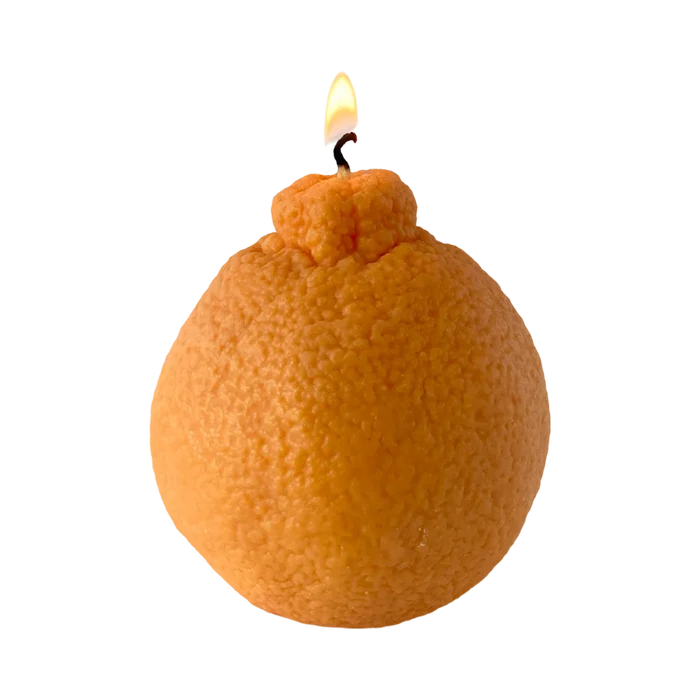 Realistic orange fruit shaped candle with green leaf detail on neutral background
