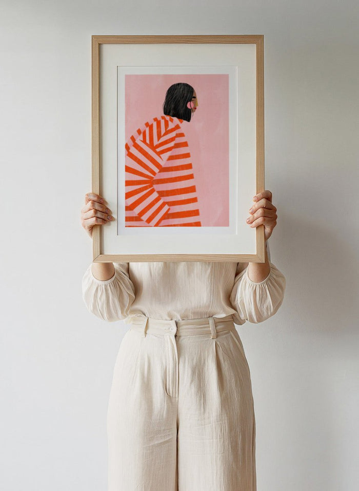 The Woman With the Orange Stripes by Bea Müller is an officially licensed art print featuring bold orange stripes and a modern illustrated woman. Available framed or unframed.