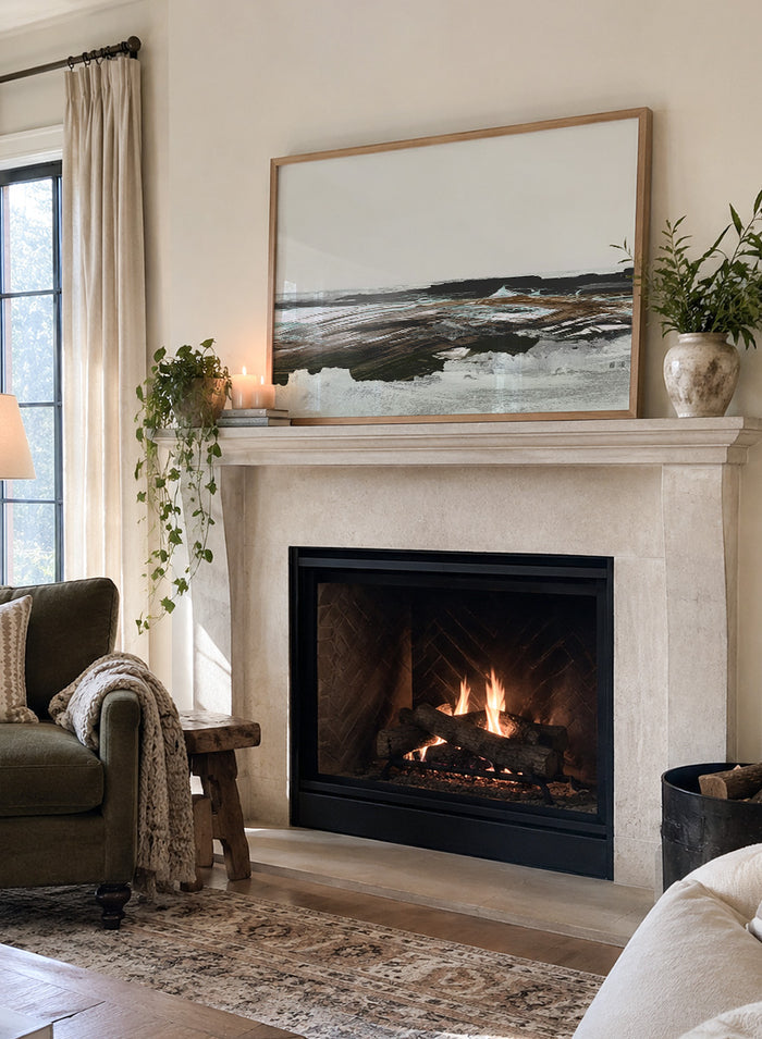 A framed abstract landscape art print featuring textured brushstrokes of brown, white, gray, and black. Shop Constantine Bay by Dan Hobday, a contemporary coastal wall art print with abstract shoreline forms, pale blue accents, dark brown tones, and textured brushwork.