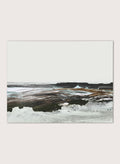 A framed abstract landscape art print featuring textured brushstrokes of brown, white, gray, and black. Shop Constantine Bay by Dan Hobday, a contemporary coastal wall art print with abstract shoreline forms, pale blue accents, dark brown tones, and textured brushwork.