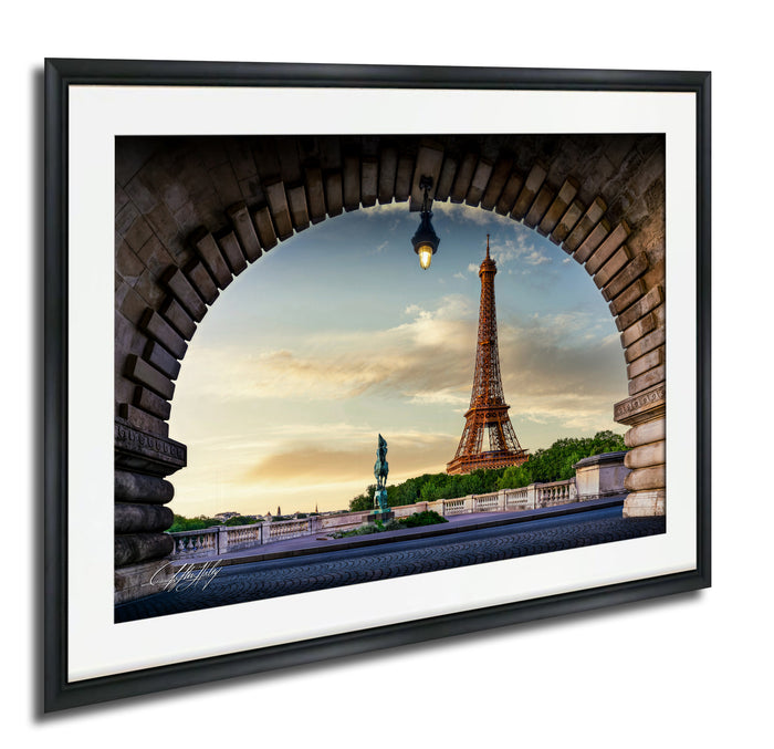 a framed photograph of the Eiffel Tower in Paris, France, with a stone archway framing the view of the iconic landmark.