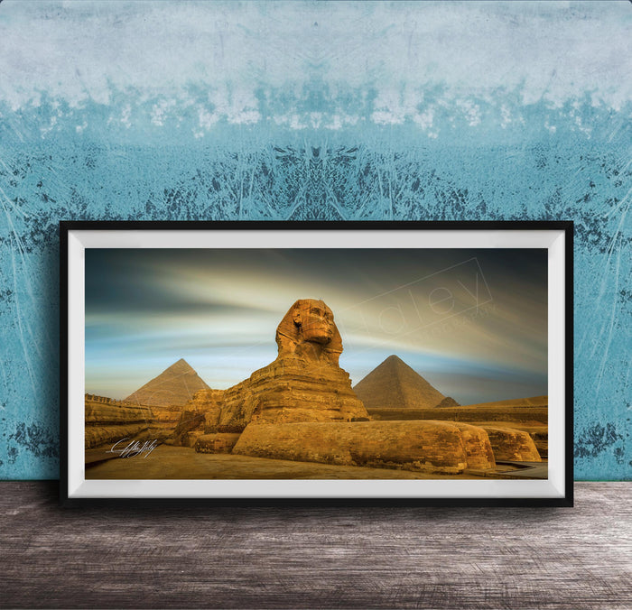 a framed photograph of the Great Sphinx of Giza, a large limestone statue of a mythical creature, in front of the pyramids of Giza in Egypt.
