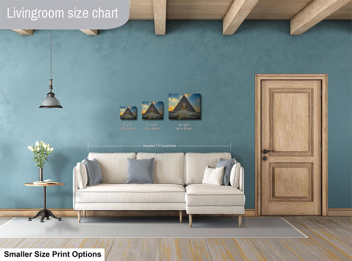 a living room with a white sofa, a wooden door, and a potted plant. There are three paintings of varying sizes displayed on the wall above the sofa.