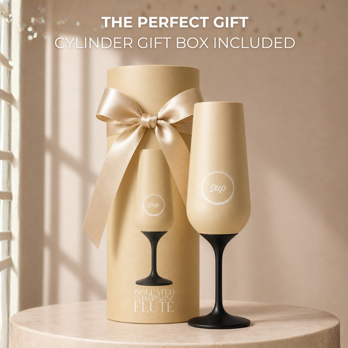 insulated champagne flute with black base and matching cylindrical gift box with bow on a neutral background