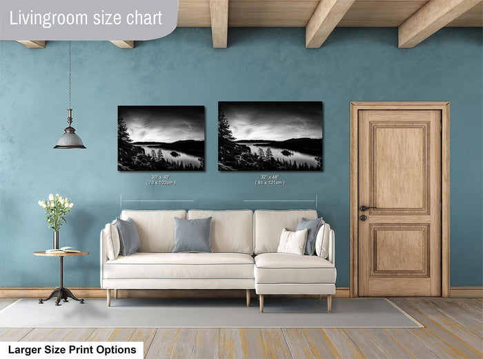 a living room with a white sofa, a wooden door, and two framed landscape photographs hanging on the wall.