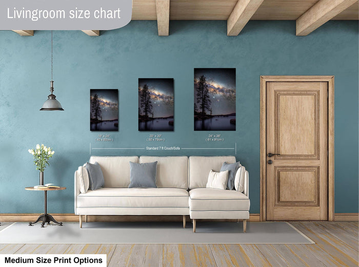 a living room with a white sofa, a wooden door, and a painting of a landscape on the wall. The painting is of a tree and a lake, and it is described as a medium-sized print.