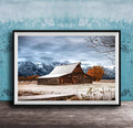 A rustic wooden barn stands in a snowy landscape, with snow-capped mountains in the background and a wooden walkway leading up to the barn.