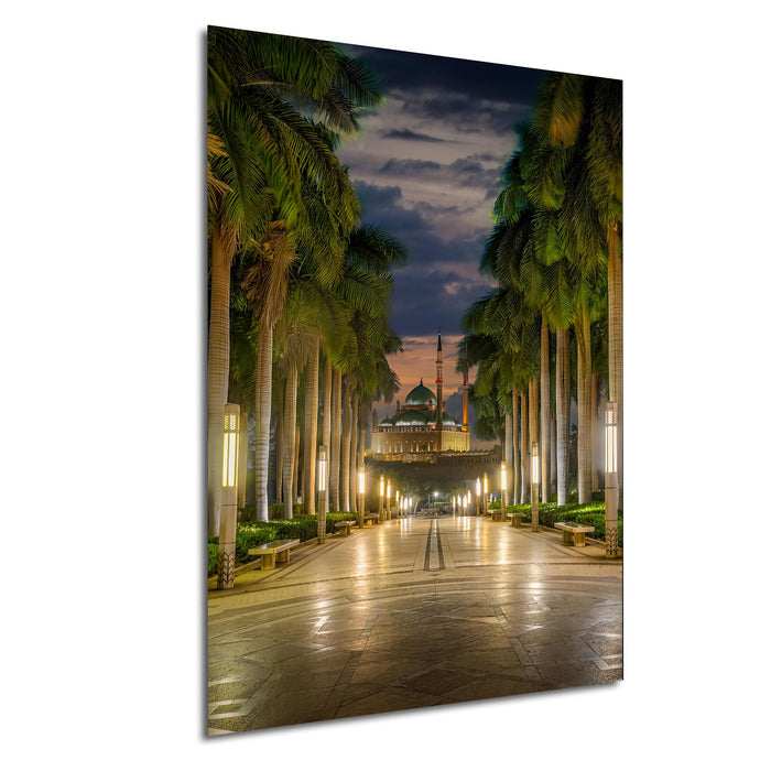 A serene night scene of a mosque with a walkway lined with palm trees, leading towards the illuminated building.
