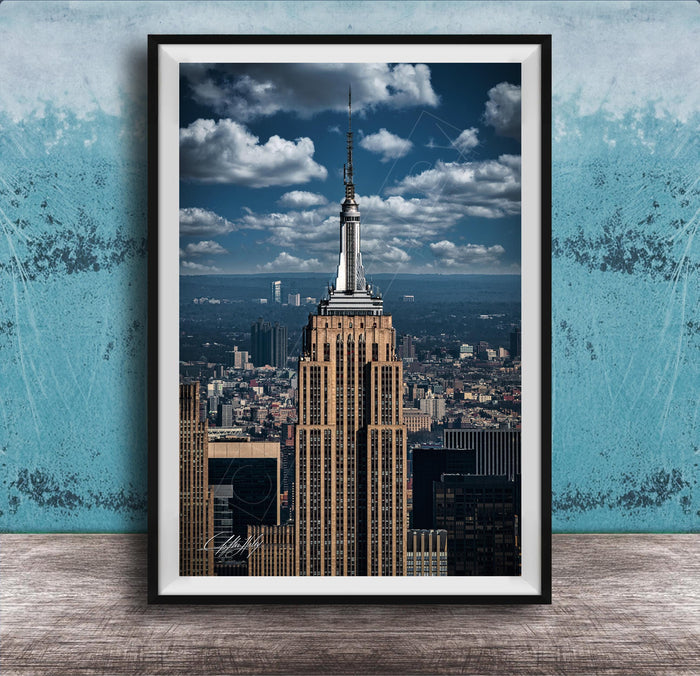 A framed photograph of the iconic Empire State Building in New York City, with the cityscape of Manhattan visible in the background.