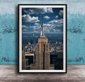 A framed photograph of the iconic Empire State Building in New York City, with the cityscape of Manhattan visible in the background.