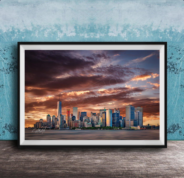 A framed photograph of the New York City skyline at sunset, with the city's skyscrapers silhouetted against a dramatic sky filled with clouds and vibrant colors.