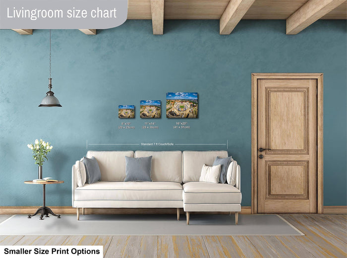 a living room with a white sofa, a wooden door, and a hanging light fixture. There are three framed artworks displayed on the wall above the sofa, each with a different size and resolution. The living room appears to be designed for a smaller space, with the furniture and artwork arranged to maximize the available area.