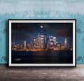 A framed photograph of the New York City skyline at night, with the city's iconic landmarks illuminated against a dark sky.