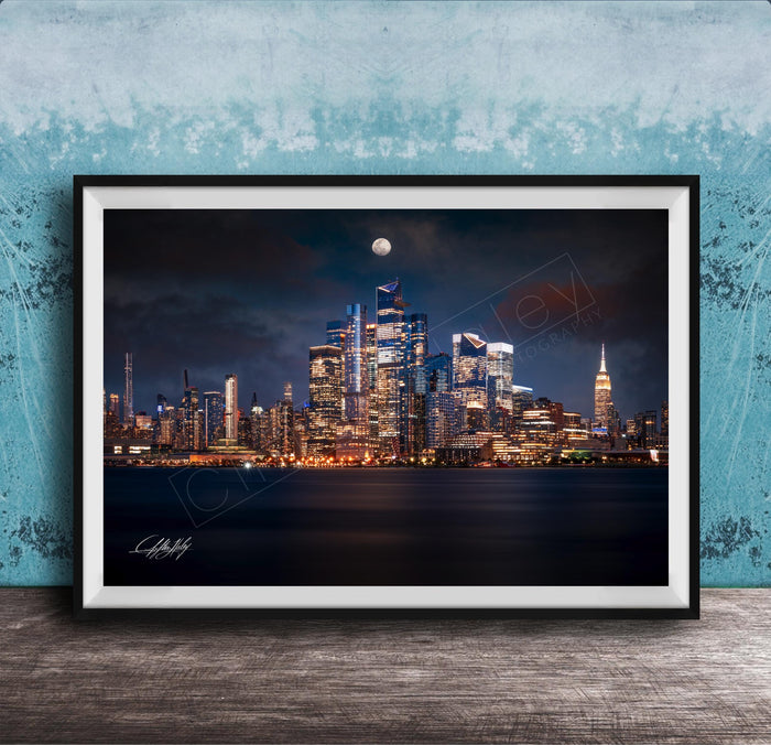 A framed photograph of the New York City skyline at night, with the city's iconic landmarks illuminated against a dark sky.