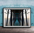 The image is a framed photograph of a long pier with multiple wooden columns extending into the distance, creating a sense of depth and perspective.