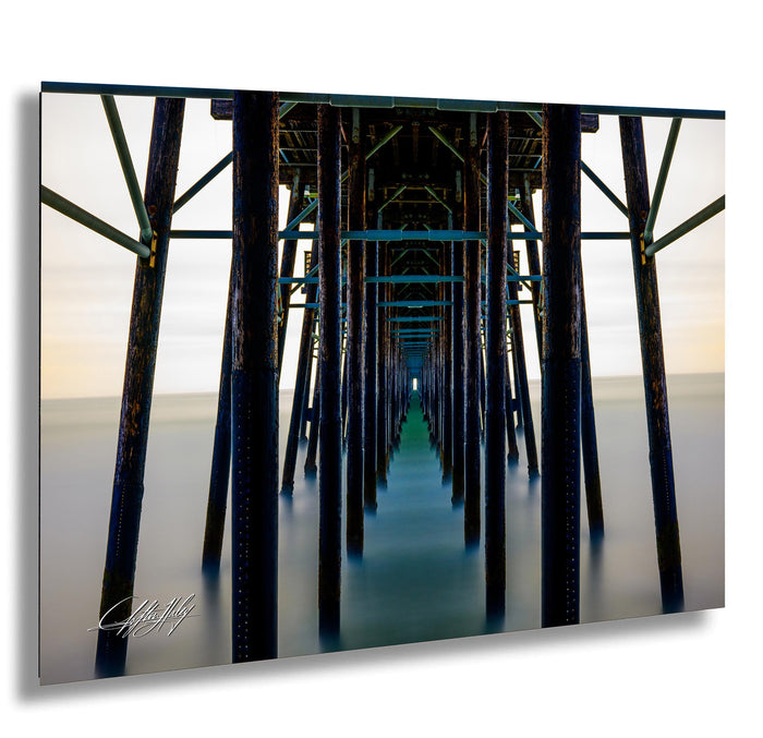 A long, wooden pier extends into the distance, with a series of dark wooden posts and beams stretching out into the water.