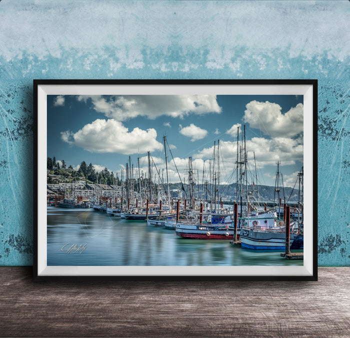 A framed photograph of a harbor with numerous sailboats docked in the water, set against a backdrop of a cloudy sky.