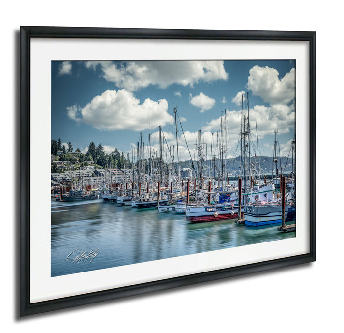 A framed photograph depicting a harbor filled with numerous sailboats docked in the water, with a cloudy blue sky overhead.