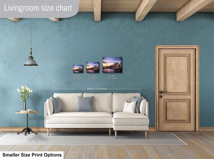 a living room with a white sofa, a wooden door, and a hanging light fixture. There are three framed pictures of different sizes displayed on the wall above the sofa.