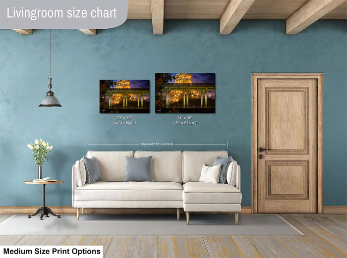 a living room with a white sofa, a wooden door, and a painting of a building with lights on the wall. The living room appears to be well-lit and decorated.