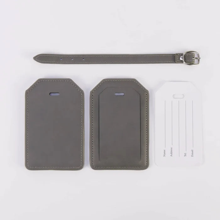 Custom grey vegan leather luggage tag shown attached to a travel suitcase