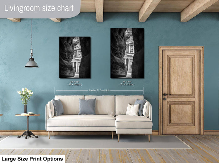 a living room with a white sofa, a wooden door, and two framed black and white photographs of a cave or rock formation on the wall.