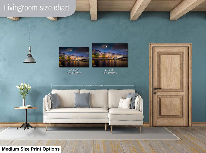 a living room with a white sofa, a wooden door, and a painting of a cityscape on the wall. The painting is of a bridge and the city lights reflecting on the water. The living room appears to be well-lit and decorated with a potted plant and a vase.