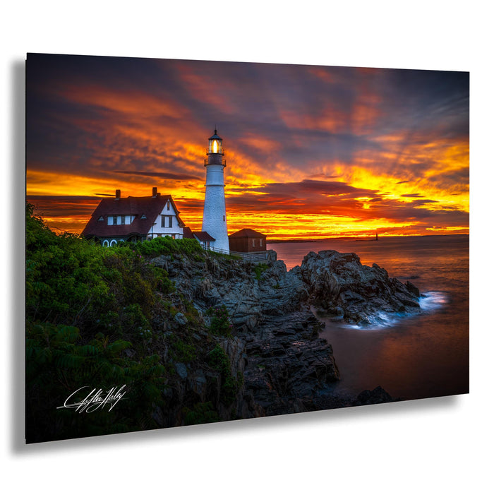 A picturesque lighthouse stands on a rocky cliff, overlooking the ocean at sunset. The sky is filled with vibrant orange and yellow hues, creating a stunning backdrop for the lighthouse. The image is a captivating blend of natural beauty and architectural charm.