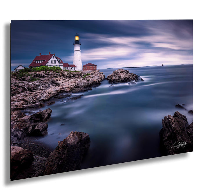 A picturesque lighthouse stands on a rocky shore, overlooking the calm, blue waters of the ocean.