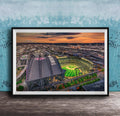 The image is a framed aerial view of a baseball stadium at night, with the stadium lights illuminating the field and surrounding area.