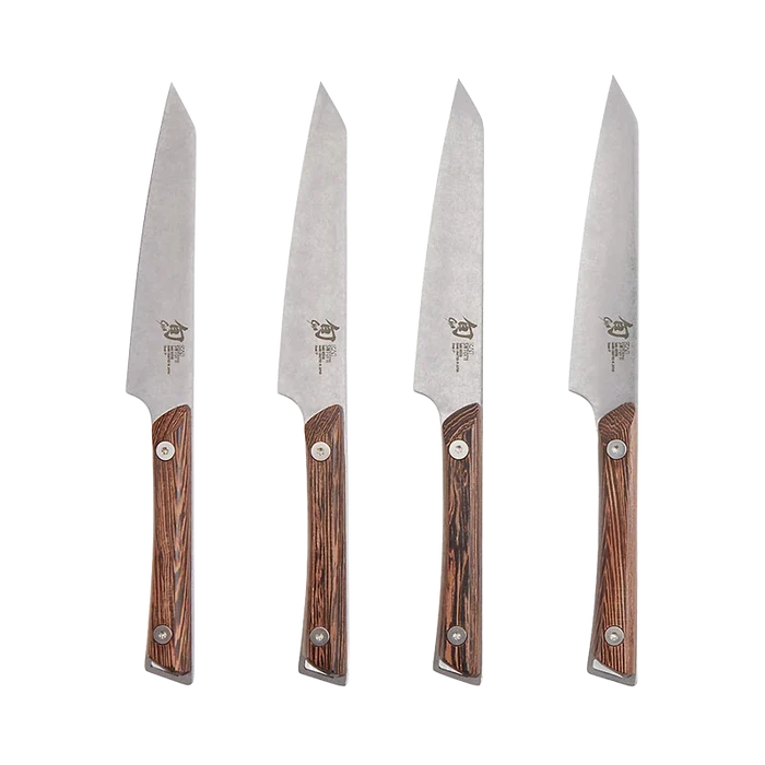 Set of four Shun Kanso steak knives with wooden handles arranged on a surface