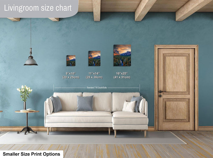 a living room with a white sofa and a wooden door. There are three framed landscape paintings hanging on the wall, each with a different size and height. The wall is painted in a light blue color, and the floor is covered with a gray rug.