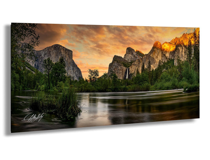 a serene landscape with a calm river reflecting the vibrant colors of the sky, surrounded by towering mountains and lush greenery.