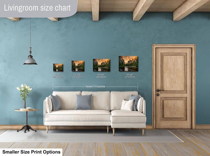 a living room with a white sofa, a wooden door, and a hanging light fixture. There are three framed landscape paintings of varying sizes displayed on the wall above the sofa.