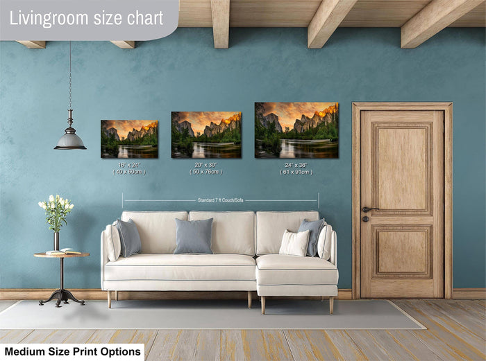 The image is a livingroom size chart with three framed landscape paintings of varying sizes, each depicting a different mountain range. The paintings are hung above a white couch, and there is a wooden door and a small table with a vase of flowers in the room.